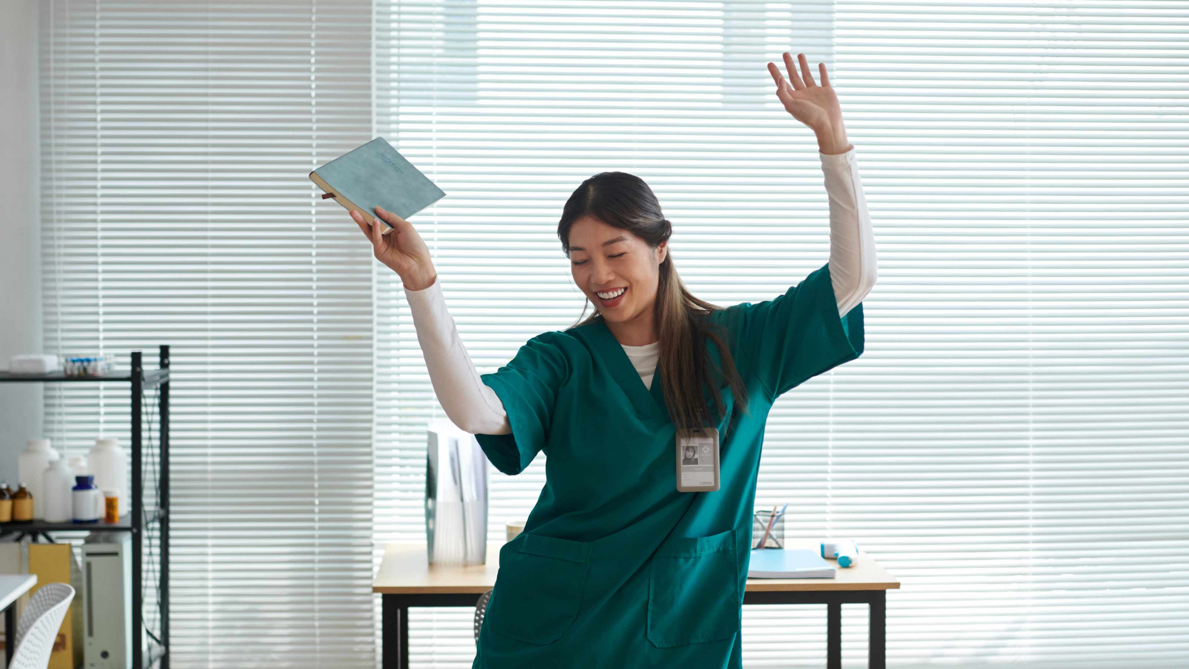 Nurse in green scrubs holding a tablet in a clinical setting